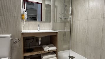 A modern bathroom with a glass-enclosed shower, a wooden vanity with a mirror, and a toilet.