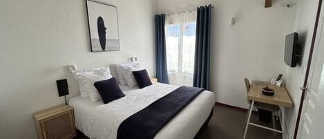 A neatly arranged bedroom with a bed, bedside tables, a desk, and a TV.
