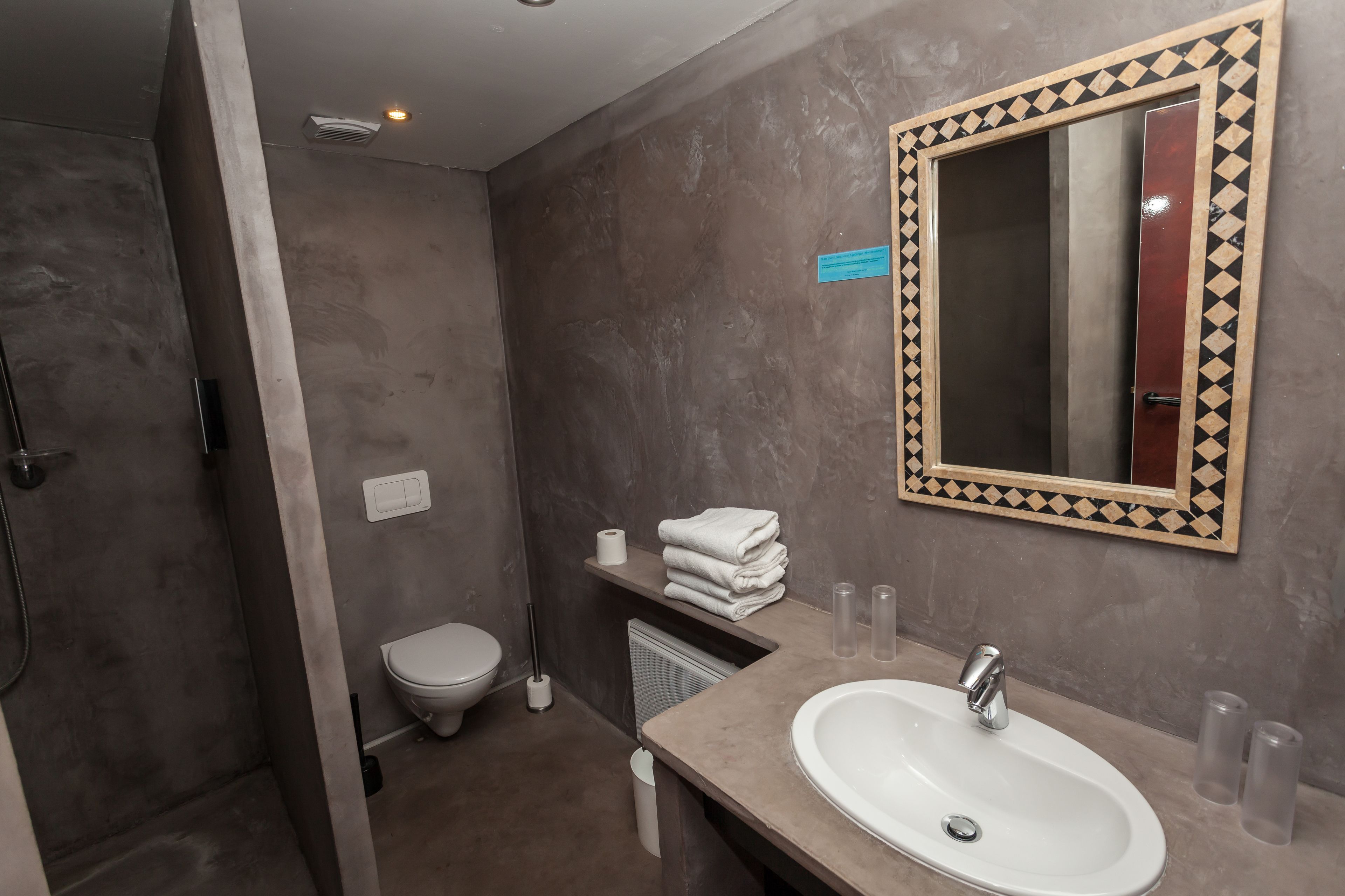 A bathroom with a sink, mirror, toilet, and shower.