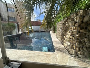 A swimming pool with a tiled deck, surrounded by a stone wall and palm trees. - Hotel De la Clape (Narbonne)