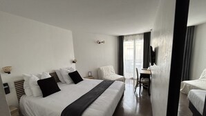 A hotel room with a large bed, a desk, and a chair.