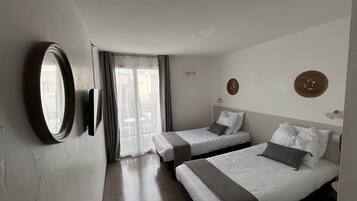 Quarto de hotel com duas camas, um espelho grande e porta de vidro deslizante para a varanda.