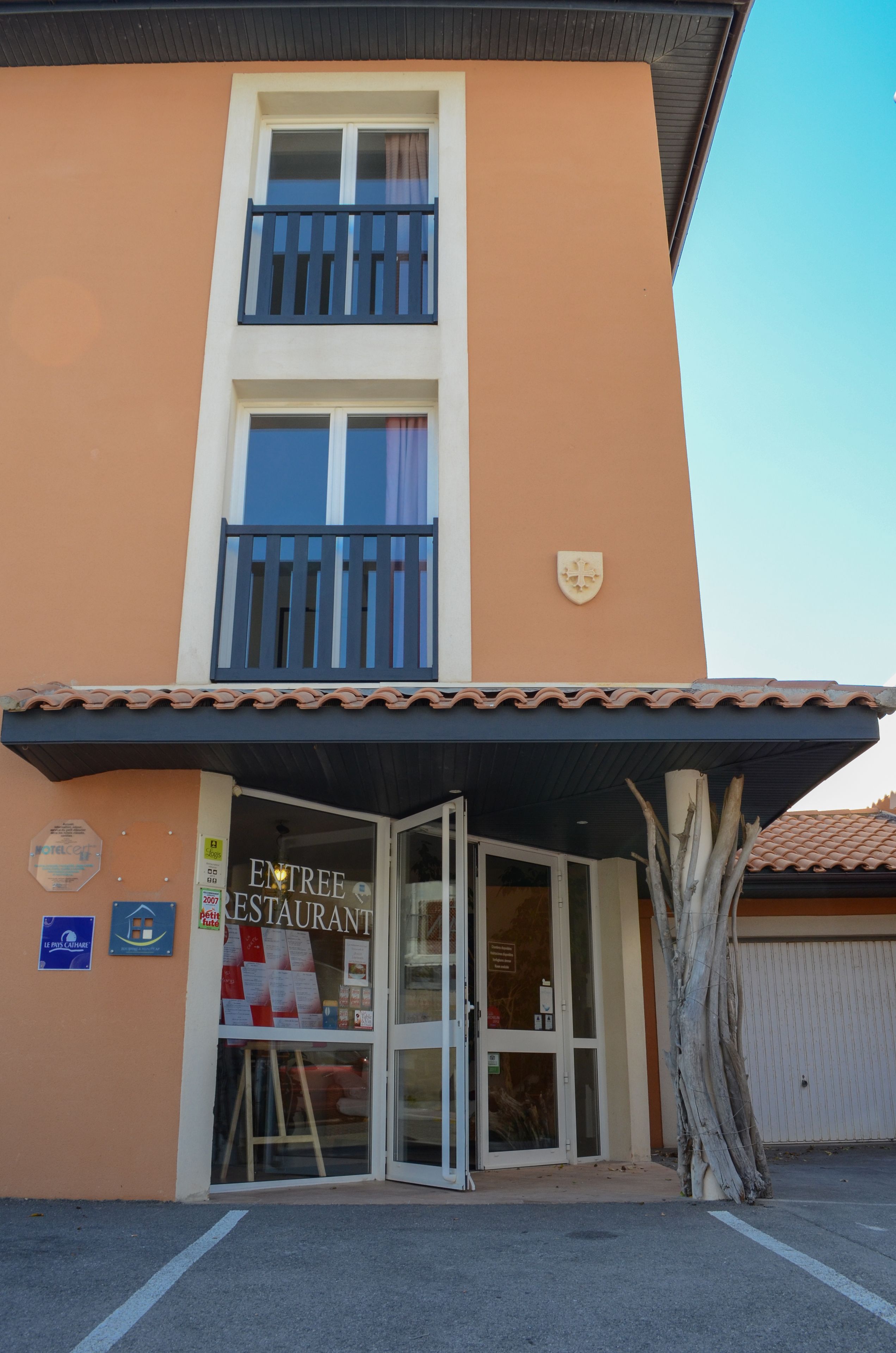 Un bâtiment à deux étages, avec une enseigne indiquant « ENTRÉE RESTAURANT » à l’entrée.