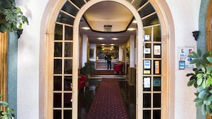 A hallway with an arched ceiling, a patterned carpet, and a reception desk. - Hotel Kristina (Imperia)