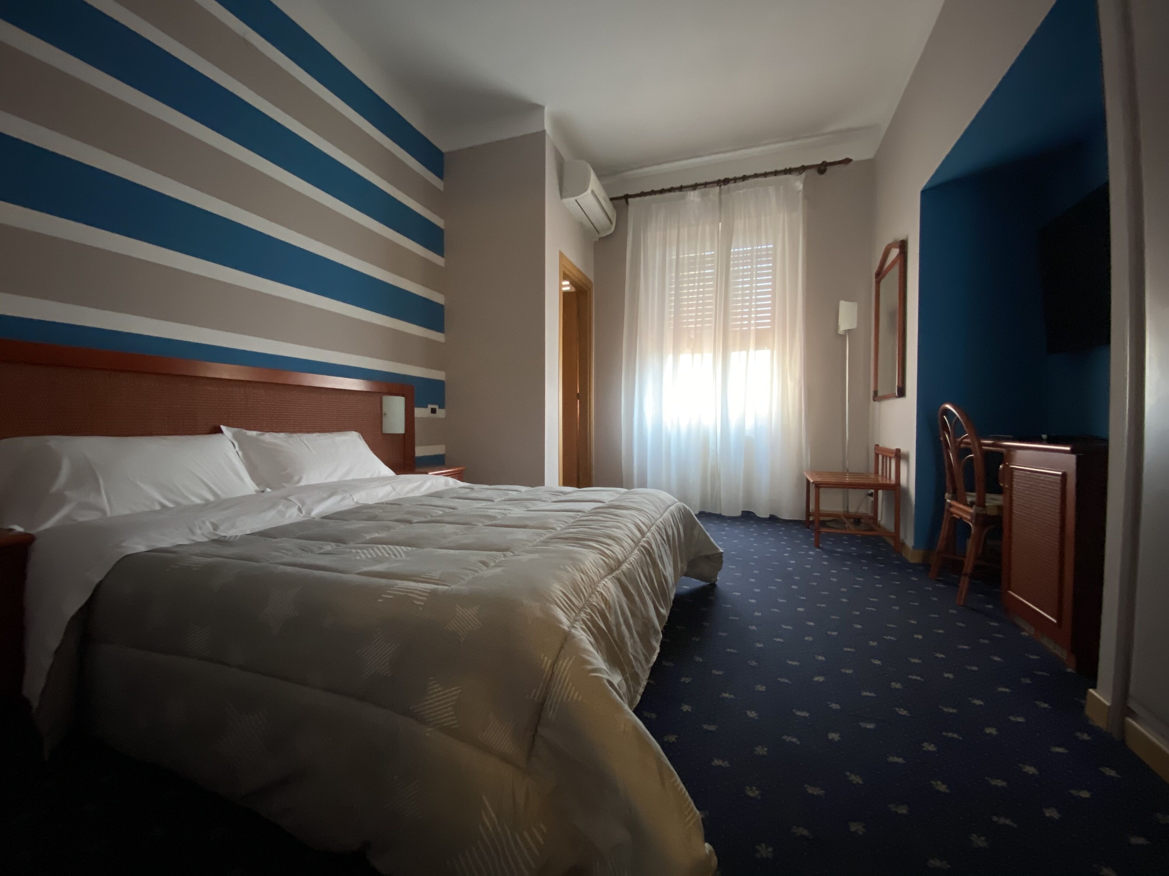 Ein Hotelzimmer mit einem großen Bett, einem Schreibtisch und einem Stuhl.