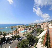 A coastal view with a beach, palm trees, and a swimming pool.