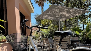 A bicycle parked outside a building with a patio area, including chairs and an umbrella. - Hotel Kristina (Imperia)