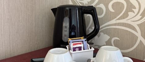 Una mesa con una cafetera, dos tazas, una bandeja y una cuchara.