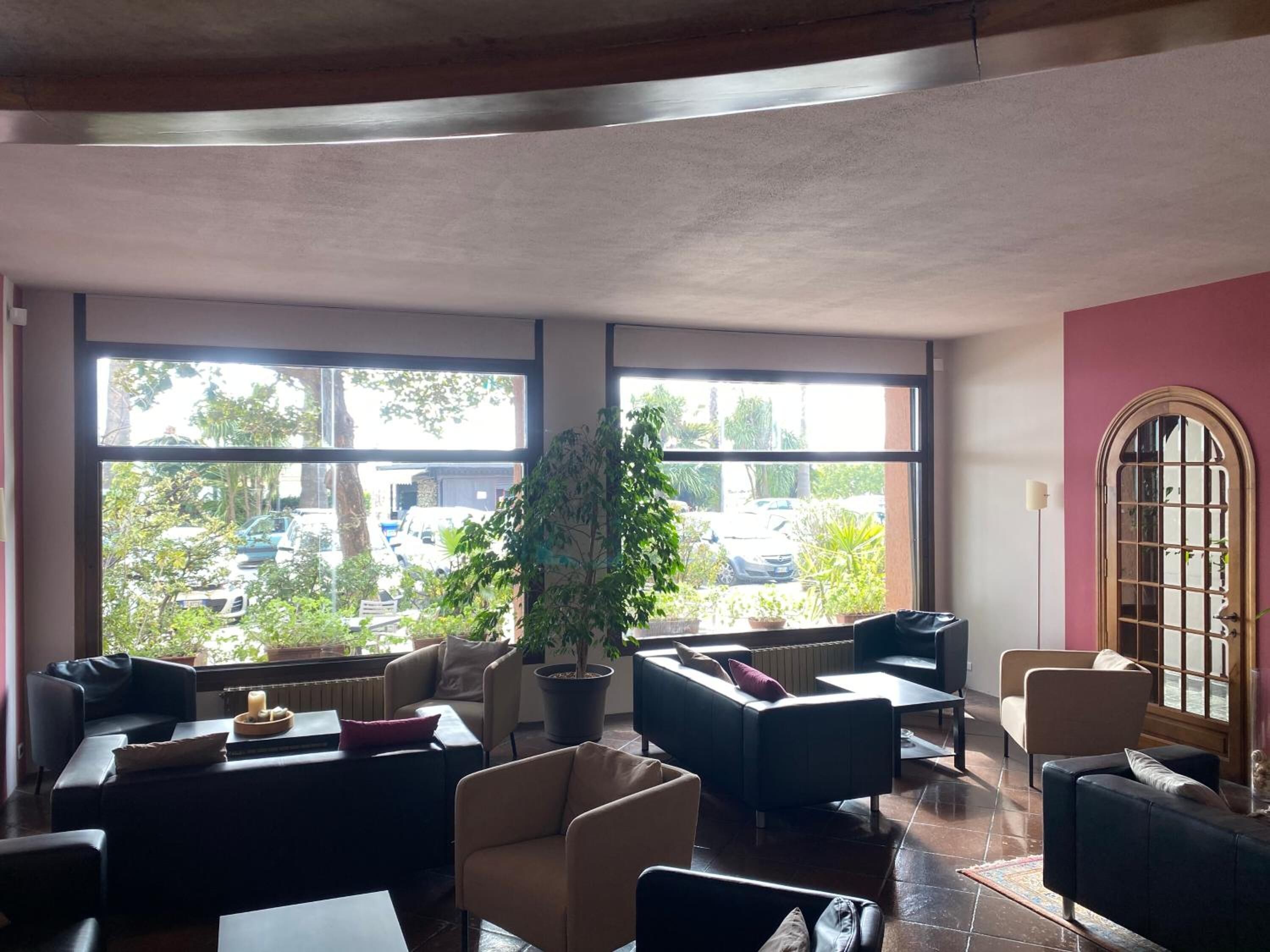 Eine geräumige Lobby mit großen Fenstern, bequemen Sitzgelegenheiten und einem Blumentopf.