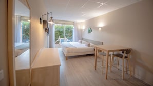 Une chambre d’hôtel moderne équipée d’un lit, d’une table de chevet et d’un bureau avec des chaises.