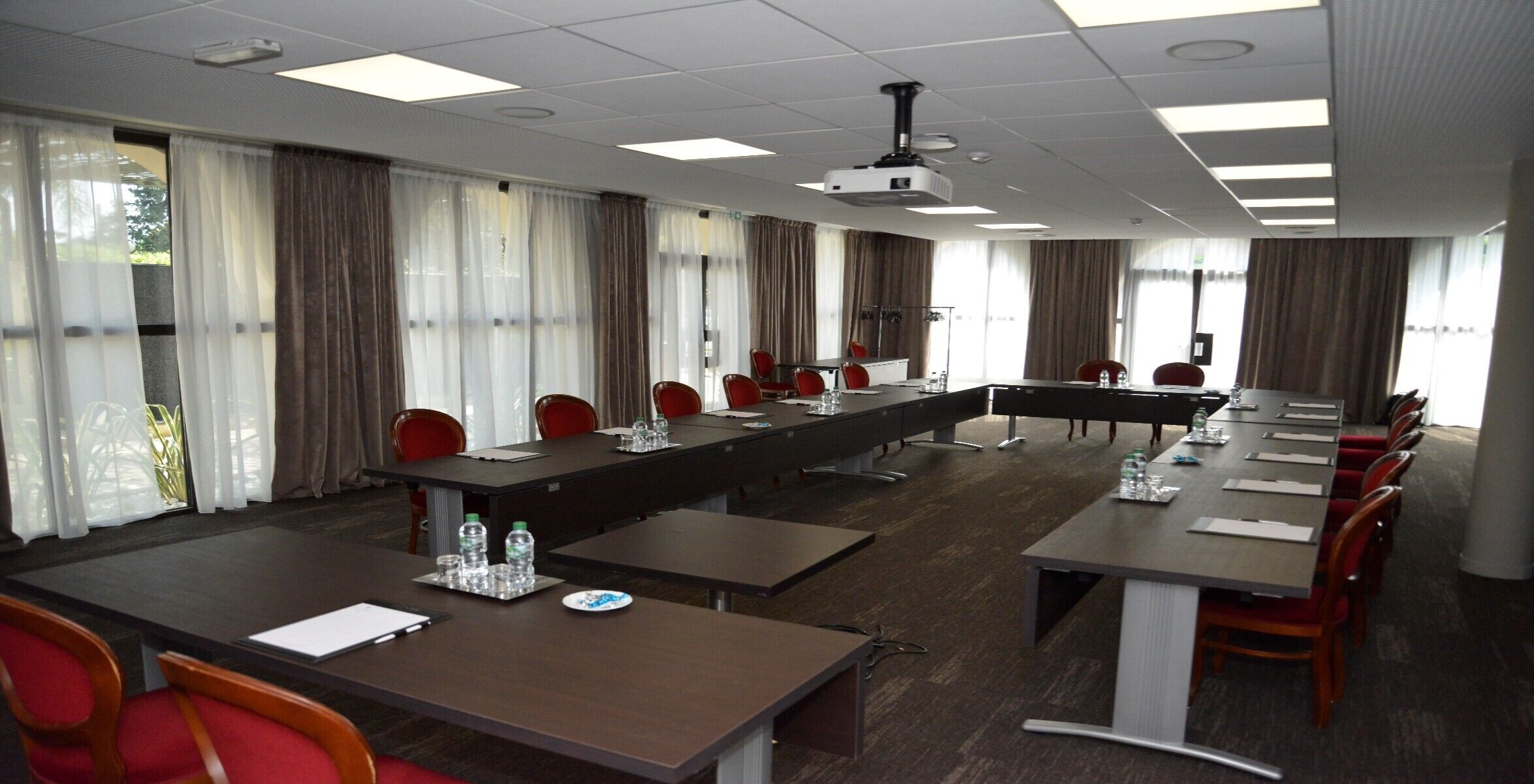 A conference room with a long table, multiple chairs, and a projector.