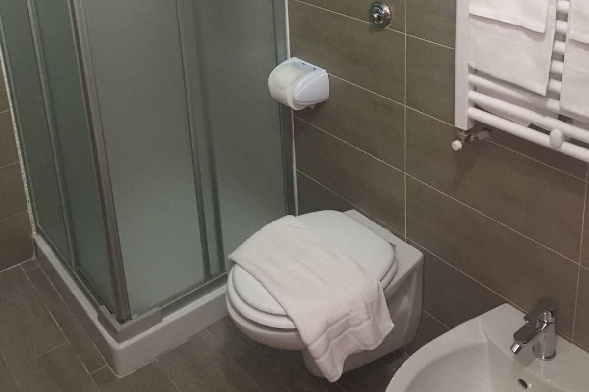 A bathroom with a glass shower enclosure, a toilet, a sink, and a towel rack.