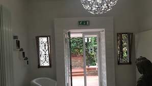 A hotel lobby with a reception desk, a white armchair, a decorative ceiling light, and a statue. - Hotel Astoria (Bordighera)