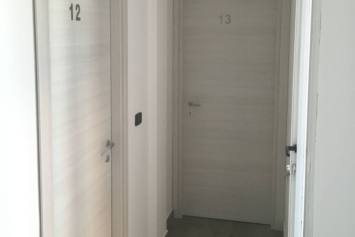 A narrow hallway with two doors, numbered 12 and 13, leading to rooms.