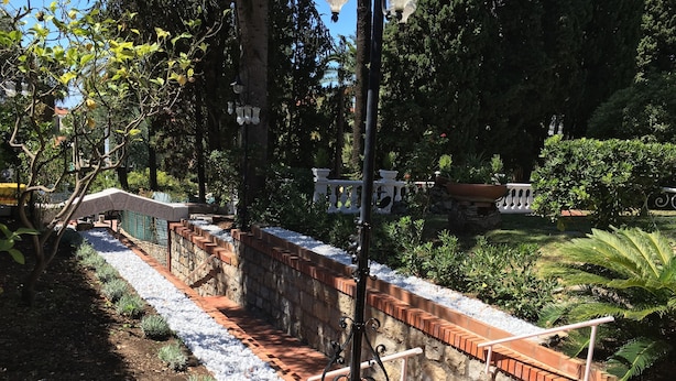 A garden pathway with a brick border, surrounded by greenery and a white fence. - Hotel Astoria (Bordighera)