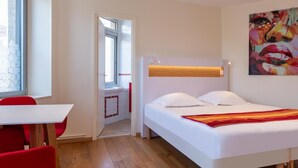 Quarto de hotel moderno com uma cama, uma escrivaninha e uma cadeira.