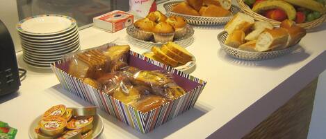 A buffet with various food items including bread, pastries, and fruits.