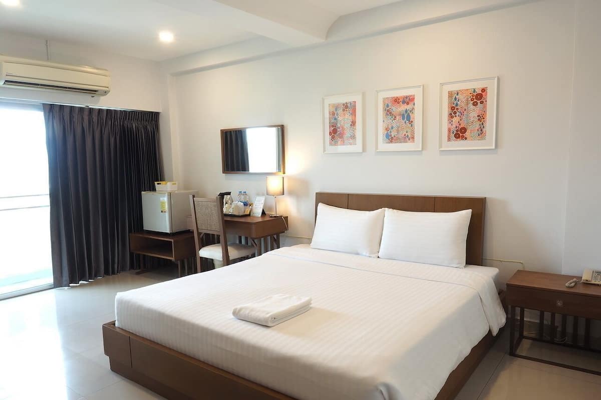 Een hotelkamer met een groot bed, een bureau met een computer, een stoel, een nachtkastje en kunst aan de muur.