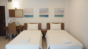 Een hotelkamer met twee bedden, een bureau, een stoel en een klein tafeltje.