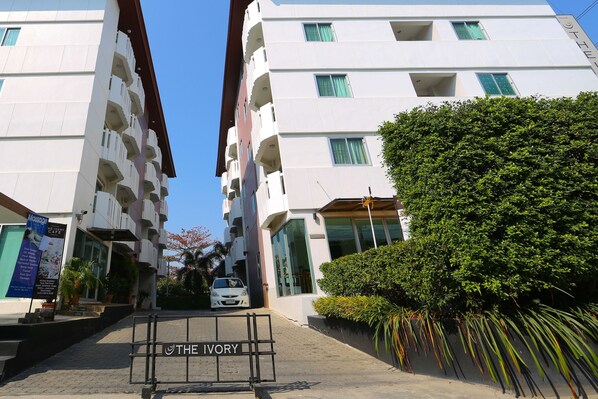 Ein modernes Hotel mit weißer Fassade, mehreren Balkonen und einem Schild mit der Aufschrift 'THE IVORY'.