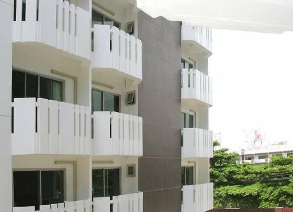 Un immeuble à plusieurs étages, doté de balcons, de grandes fenêtres et d’une façade grise.