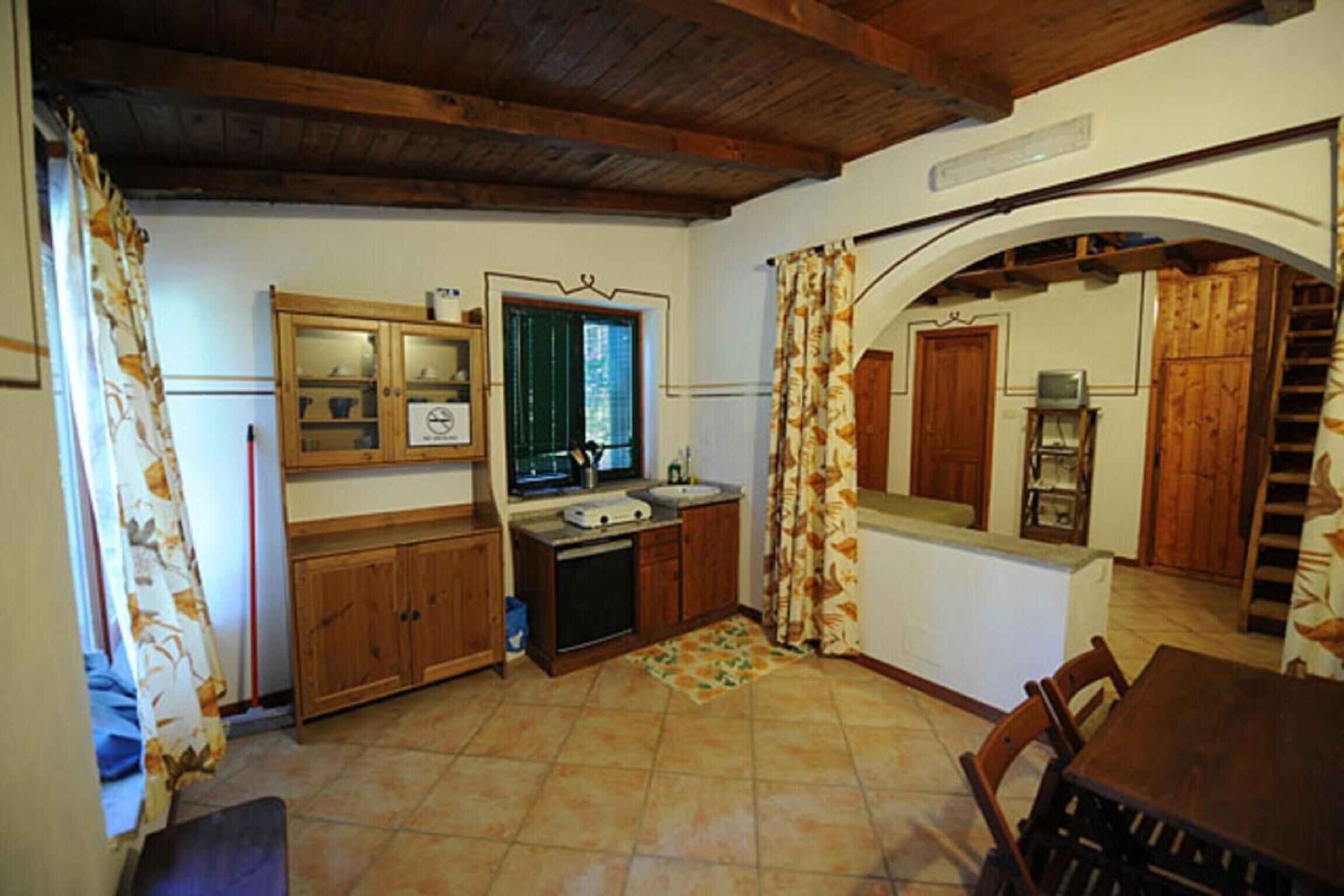 Una cucina con mobili in legno, un lavello e un'area pranzo con tavolo e sedie.