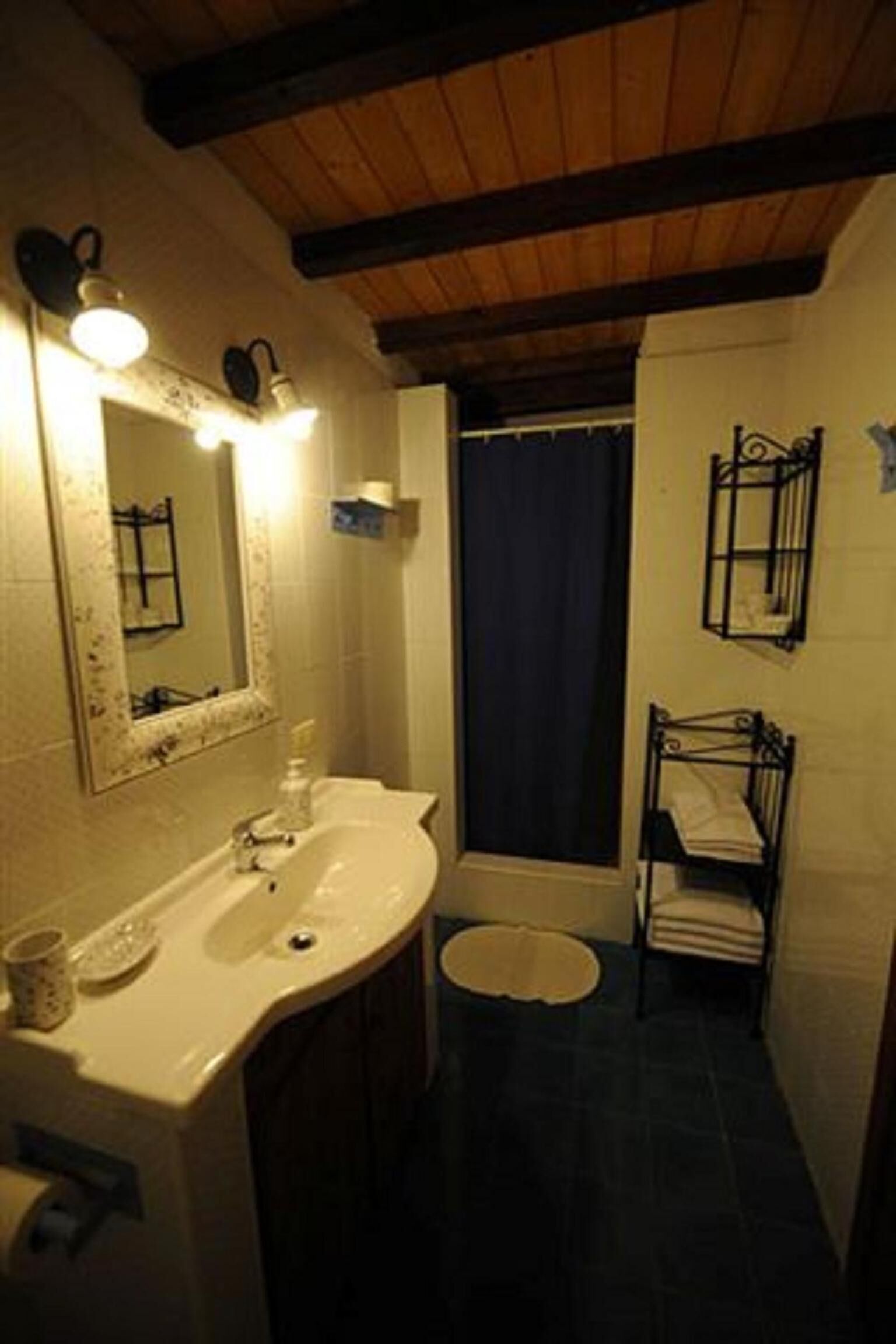 Un baño con lavamanos, espejo y toallero.