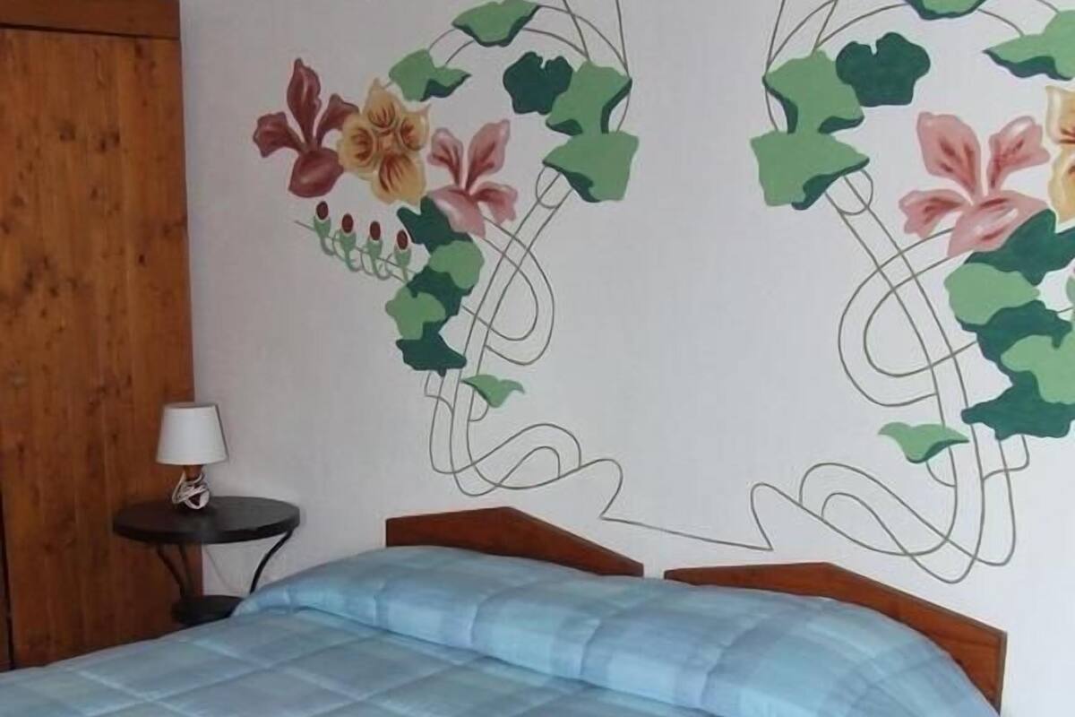 Un dormitorio con una cama, una mesita de noche y un adorno en la pared.