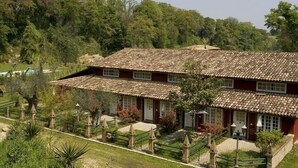 Un edificio a due piani con tetto in tegole, circondato da un giardino con diverse piante e un vialetto che conduce all'ingresso.