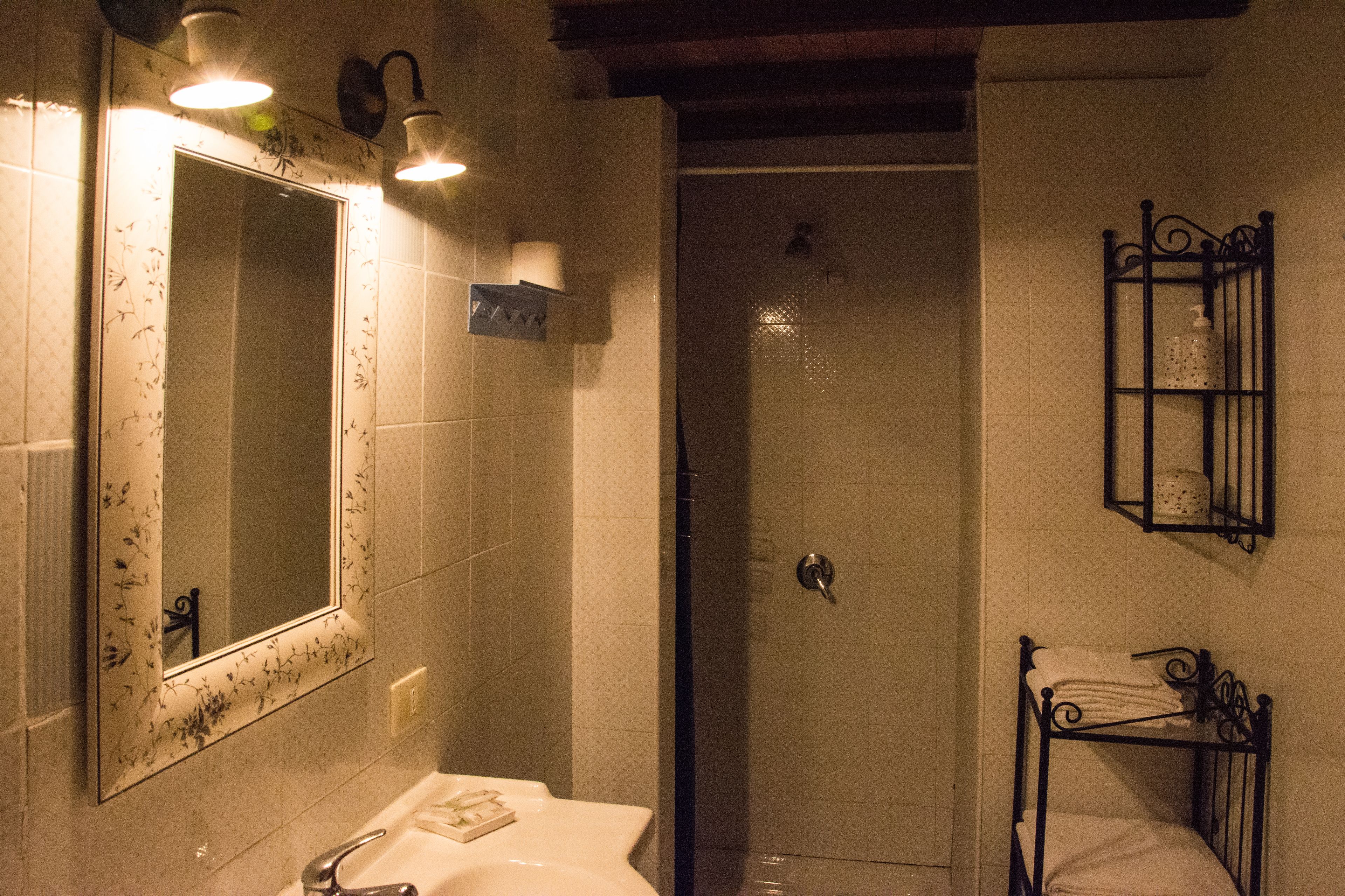 A bathroom with a sink, mirror, shower, and towel rack.