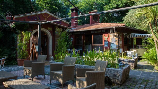 Patio esterno con mobili in vimini, angolo bar e vialetto in pietra.