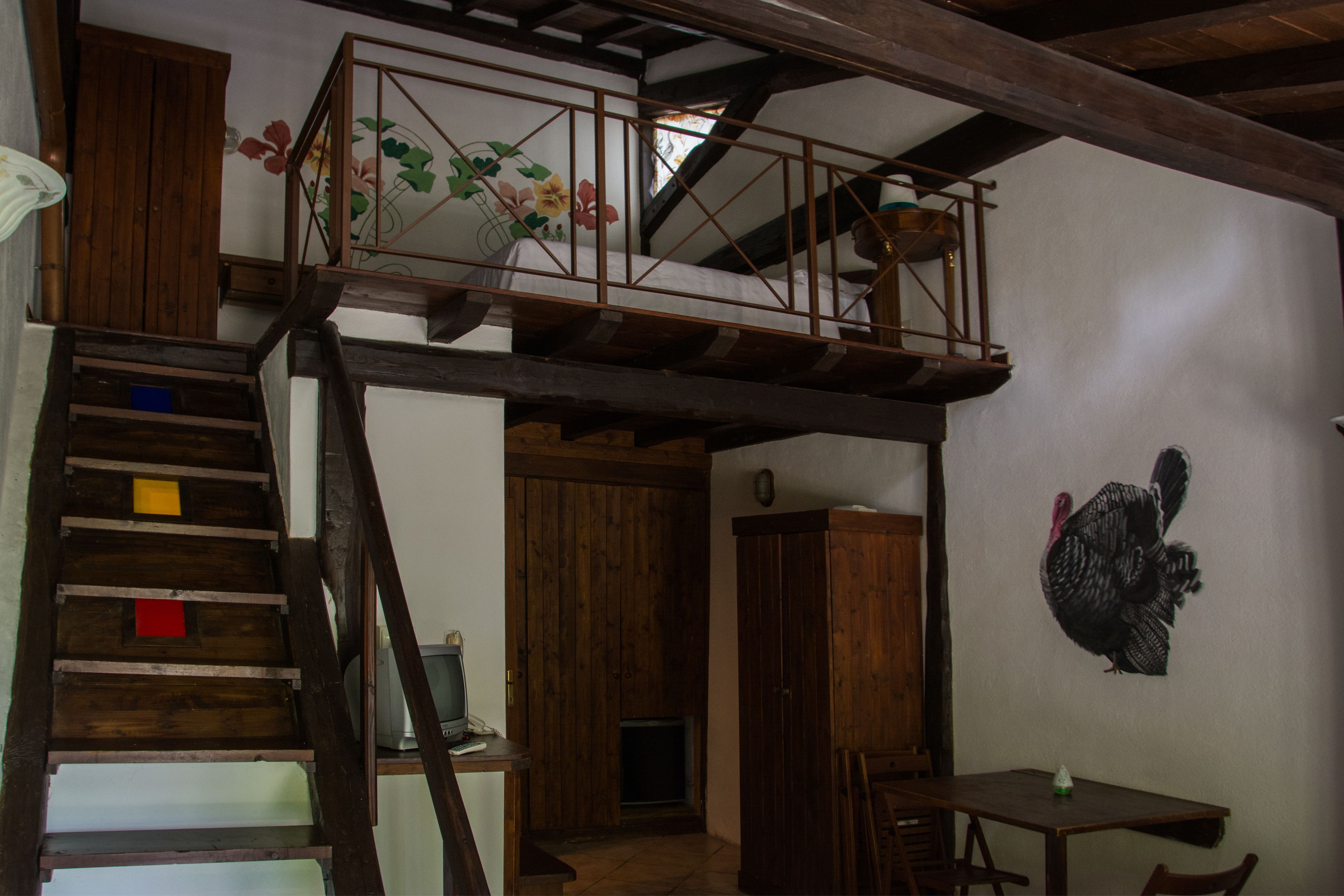 A rustic interior with a wooden staircase, a dining area, and a wall-mounted turkey decoration.