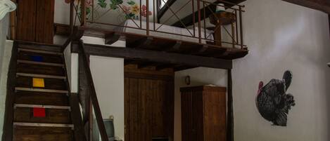 A rustic interior with a wooden staircase, a dining area, and a wall-mounted turkey decoration.