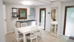 Una cucina compatta con mobili bianchi, forno integrato e finestra sopra il lavello.