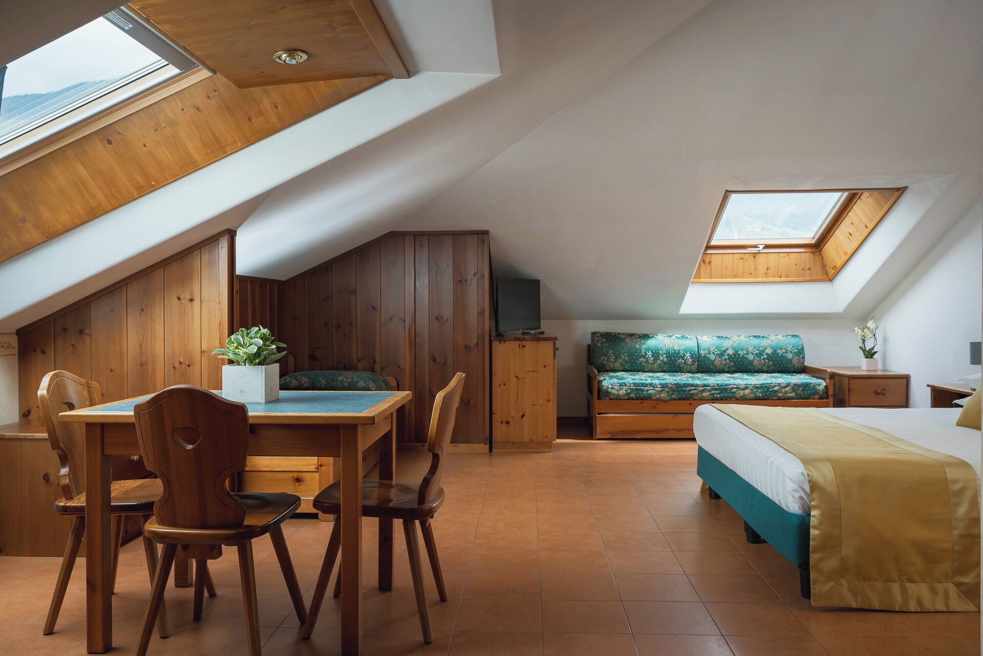 Un dormitorio acogedor en el ático con una mesa de comedor de madera, sillas, un sofá y una cama.