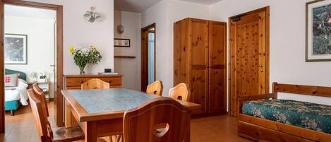 A cozy room with a wooden dining table, chairs, a sofa, and a bed.
