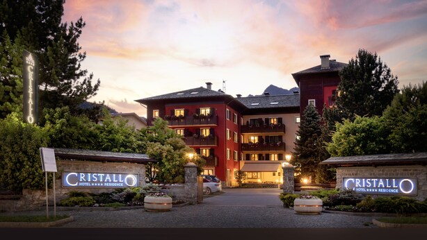 A hotel entrance with a sign reading "Cristallo Hotel Residence" and a stone wall with the same sign. - Cristallo Hotel Residence (Bormio)