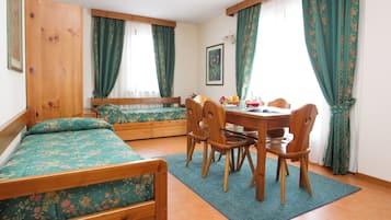 Een kamer met een bed, een eettafel met stoelen en een raam met gordijnen.