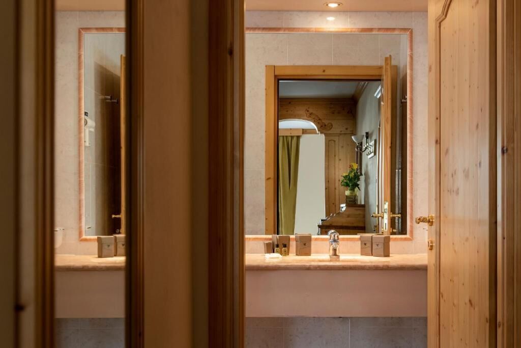 Un baño con tocador de madera, espejo y lavamanos.