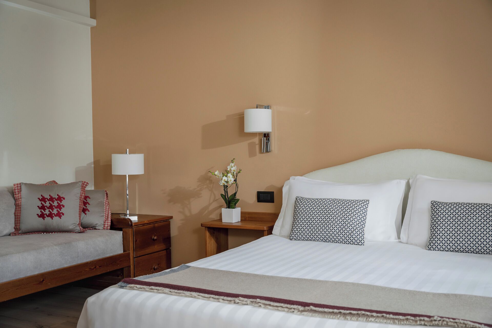 Una habitación de hotel con una cama, una mesita de noche, una lámpara y un velador.