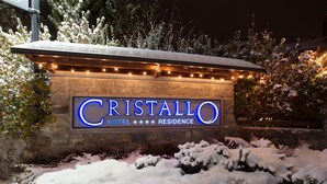 A sign for Cristallo Hotel with a stone facade and string lights. - Cristallo Hotel Residence (Bormio)