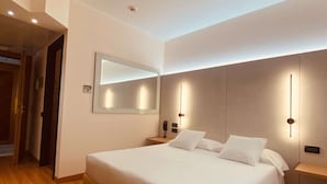 A modern bedroom with a large bed, bedside tables, a mirror, and a built-in bench. - Best Western Hotel Solaf (Medolago)