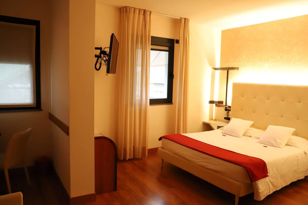 A hotel room with a large bed, a desk, and a chair.
