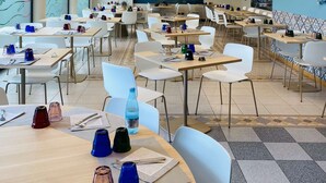 A spacious dining area with multiple tables and chairs, modern pendant lighting, and large windows offering views of greenery. - Best Western Hotel Solaf (Medolago)