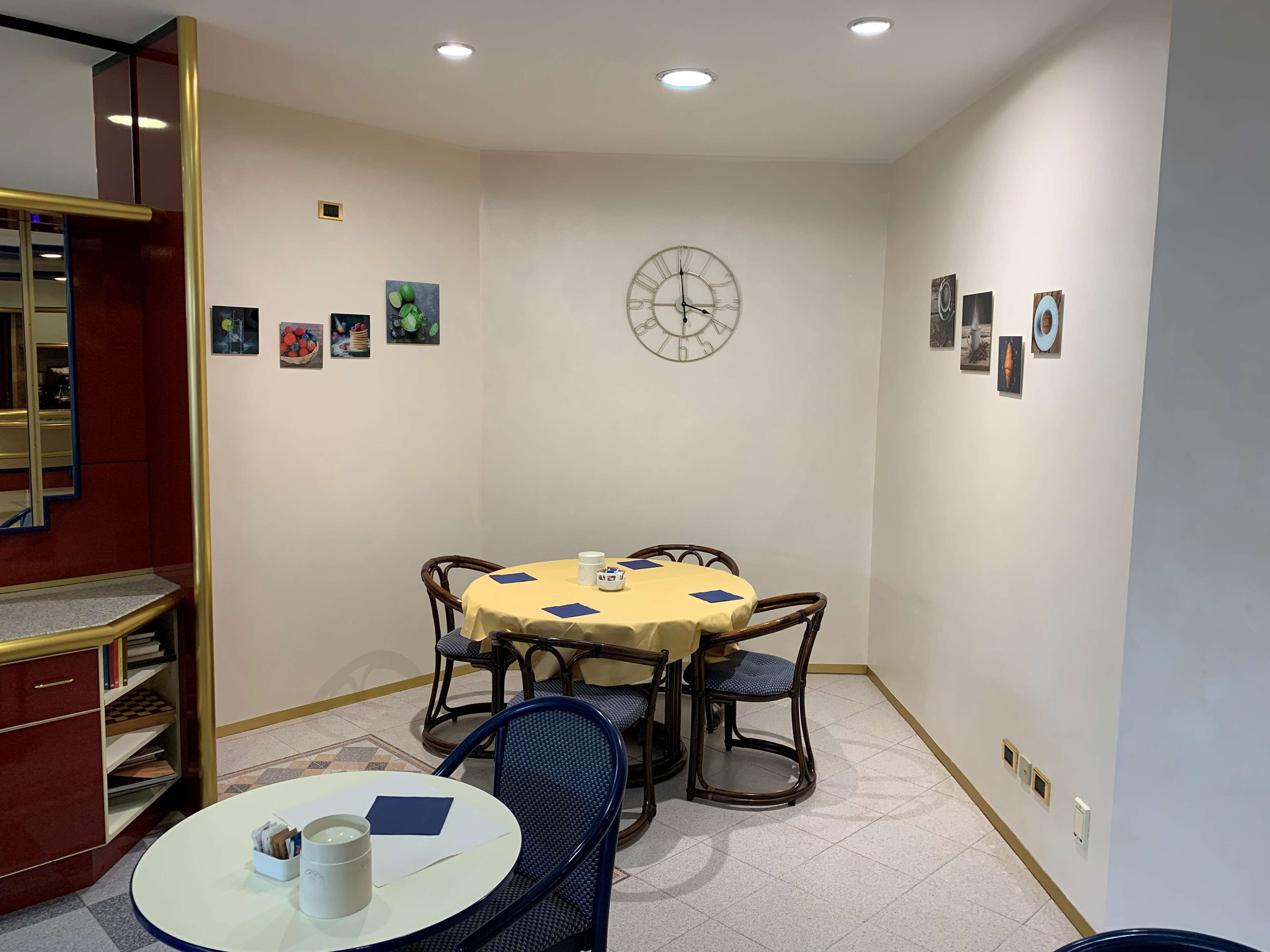 Un coin repas avec une table ronde, des chaises, une horloge et des tableaux encadrés accrochés au mur.