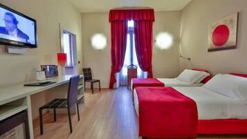 A hotel room with two beds, a desk, and a TV.