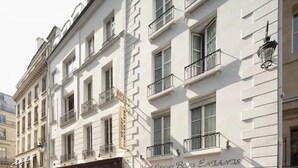A white building with balconies and a sign that reads "Hotel Louise Bar & Restaurant". - Hôtel Louvre Bons Enfants (Paris)