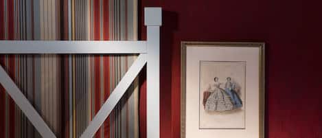 A framed artwork of two figures on a red wall.