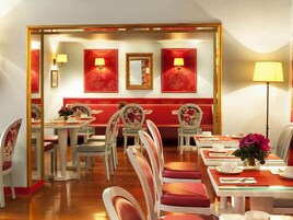 Un comedor con decoración roja y blanca, que incluye un banco, sillas y mesas.