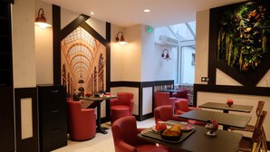 A restaurant interior with red chairs, black tables, and a large mural of a building on the wall. - Hotel Amiral Fondary (Paris)